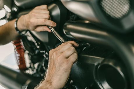 A Man Is Working on A Motorcycle with A Wrench — Dent Motive In Nerang, QLD