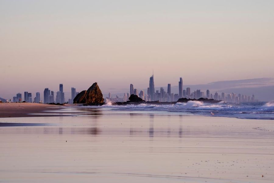 A Beach with A City Skyline in The Background and A Rock in The Foreground — Dent Motive In Broadbeach, QLD