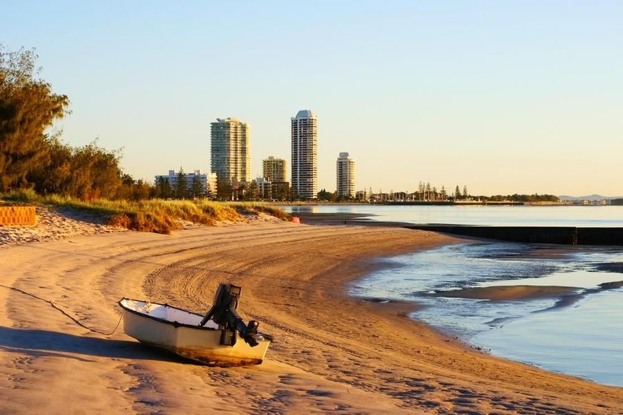 A Small Boat Is Sitting on the Beach Near the Water — Dent Motive In Runaway Bay, QLD