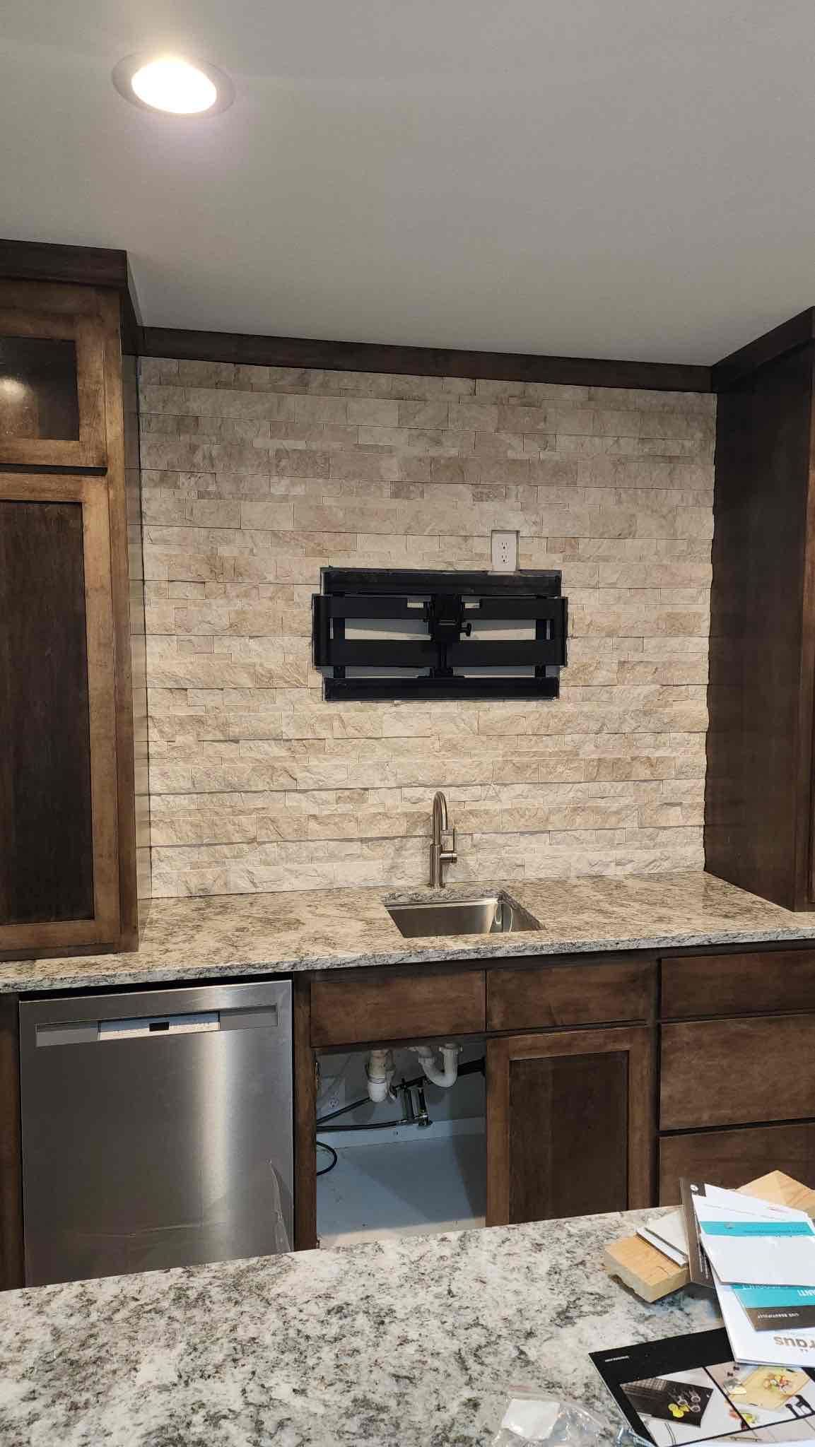 Kitchen with a stone backsplash, sink, dark cabinets, and stainless steel appliances.