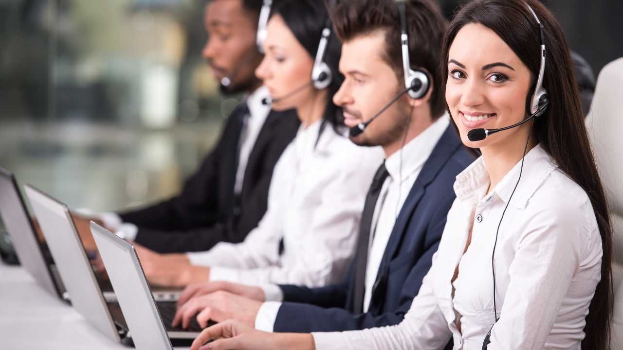 A group of people wearing headsets are working in a call center.