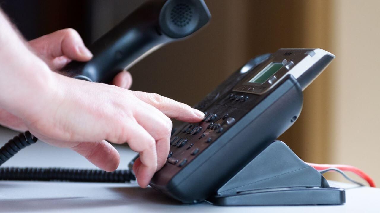 A person dialing a number on a telephone.