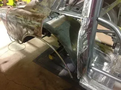 Damaged car body panels in a workshop, with exposed metal and primer during repair