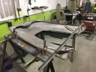 Large metal sheet on a frame in a workshop, with clamps and tools around it
