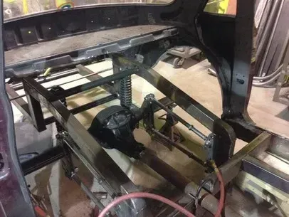 Custom metal frame and mechanical assembly inside a vehicle interior, with wiring and tools visible.