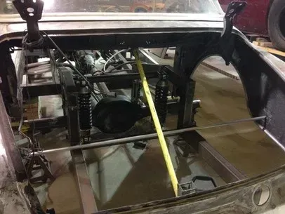 Damaged car interior with exposed frame and a yellow measuring stick across the front seat area