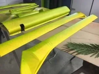Yellow-painted industrial parts stacked on a floor beside a workbench