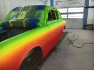 Rainbow-painted car in a garage, with green roof and front fading to orange-red sides.