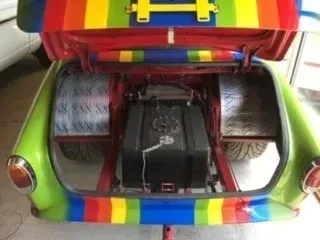 Colorful car trunk filled with speakers and audio equipment, with a rainbow-painted rear hatch open.