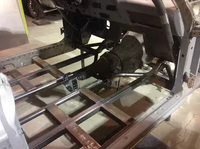 Interior of a car frame with exposed chassis and drivetrain components in a workshop