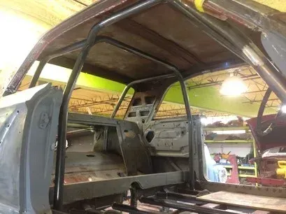 Partially stripped car interior with metal frame and gray seats in a workshop
