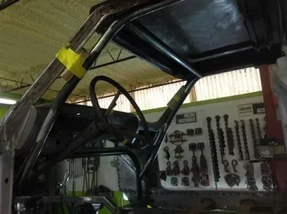Close-up of a vehicle body frame in a garage, with tools hanging on the wall behind it.