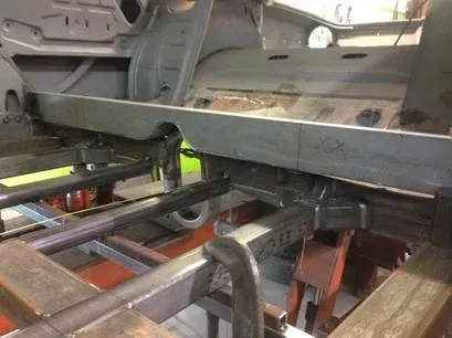 Inside a car factory, metal frame on an assembly line with welding equipment underneath