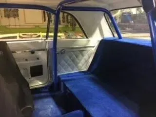 Blue upholstered back seat and door interior of a vintage car, viewed from the rear.