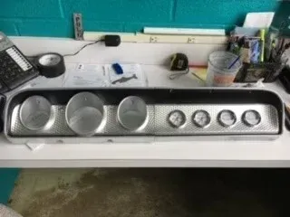 Countertop with a stainless steel control panel, six round knobs, and three large dials beneath a teal backsplash.