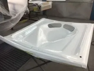 White ceramic sink basin on a worktable in a workshop or factory setting