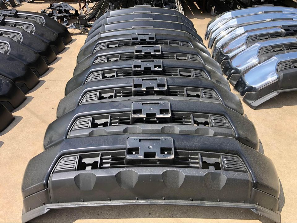 A bunch of front bumpers are lined up in a row