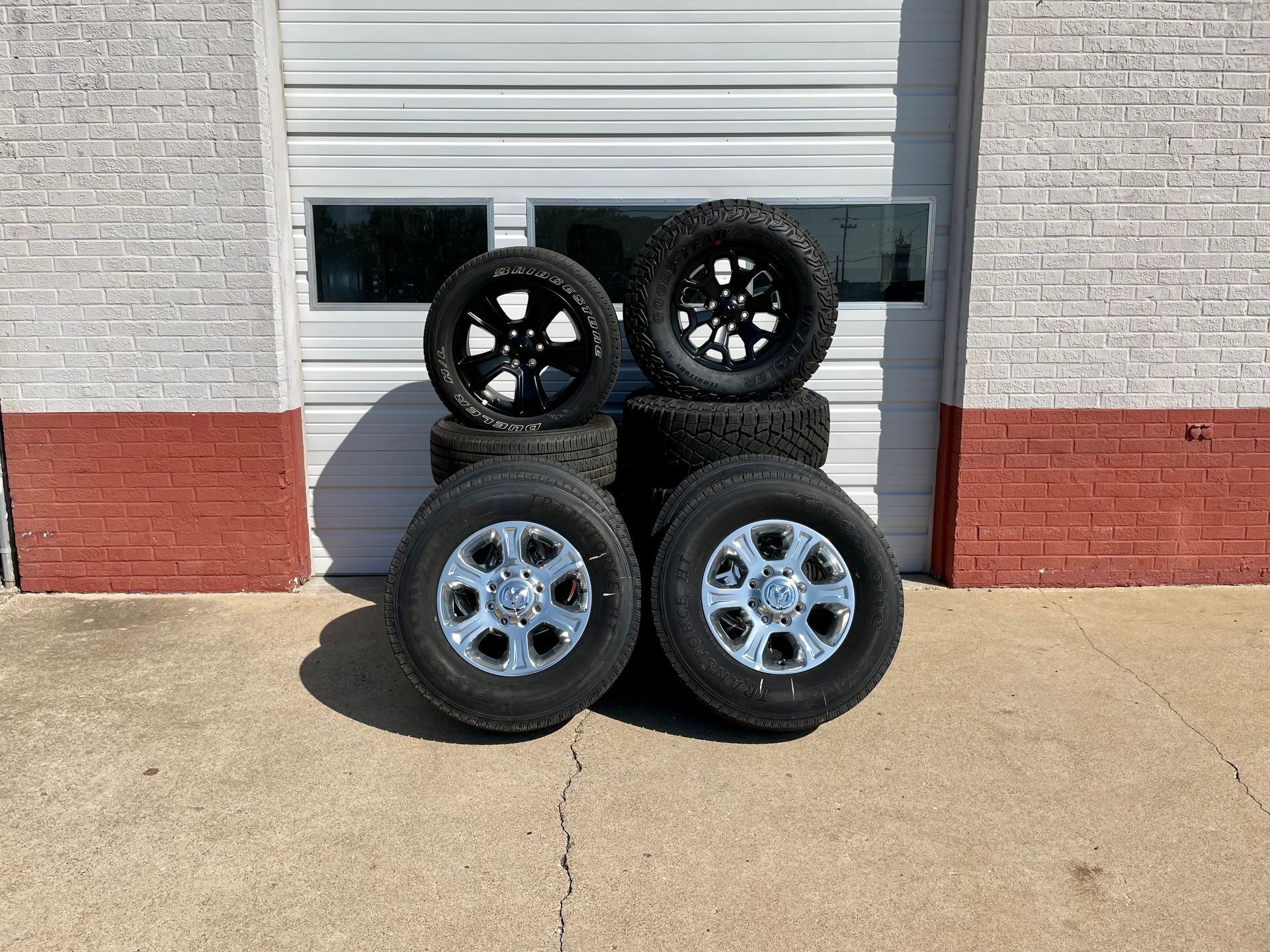 A bunch of tires are stacked on top of each other in front of a garage door.