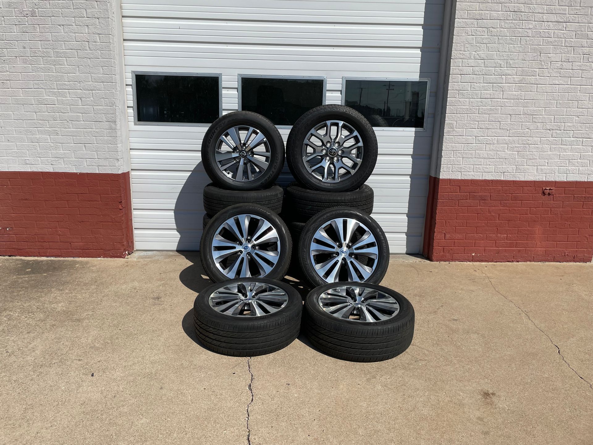 A bunch of tires are stacked on top of each other in front of a garage door.