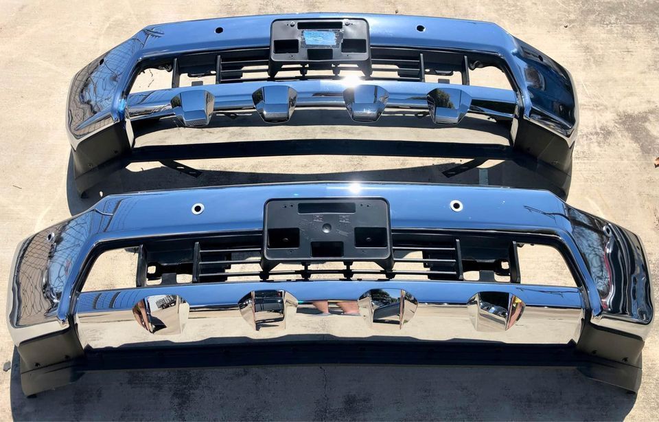 Two chrome bumpers are sitting next to each other on the ground.