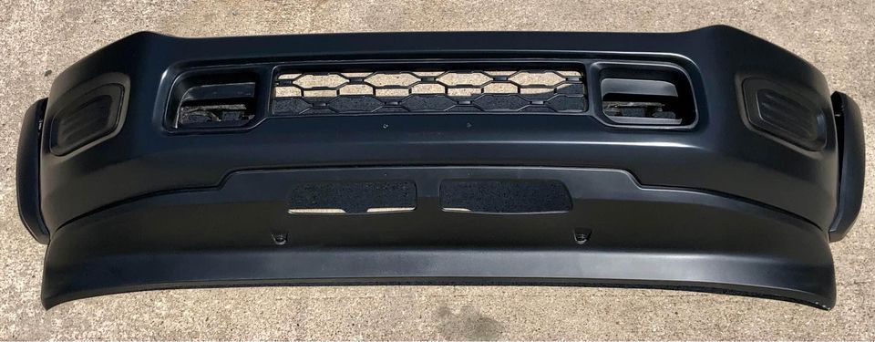 A black bumper is sitting on a concrete surface.