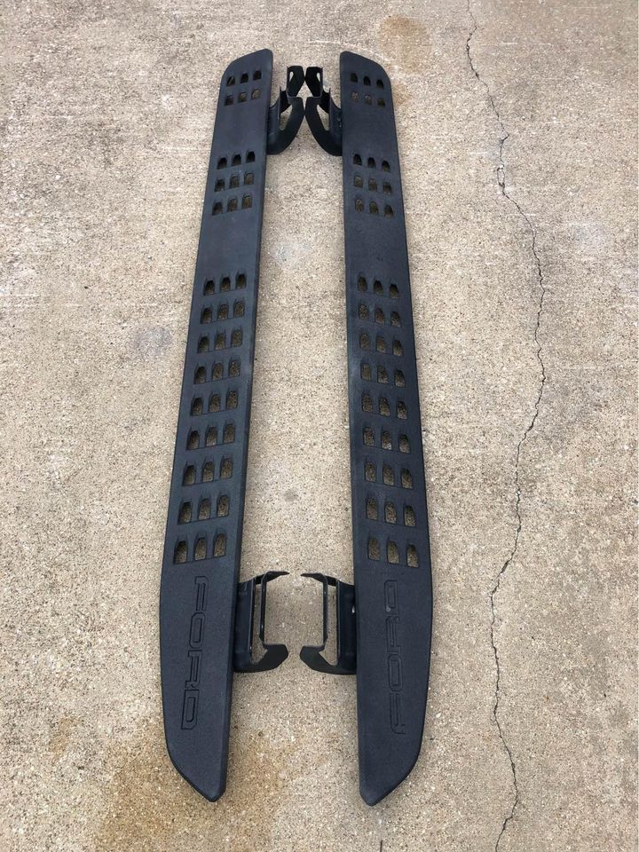 A pair of black side steps are sitting on top of a concrete surface.