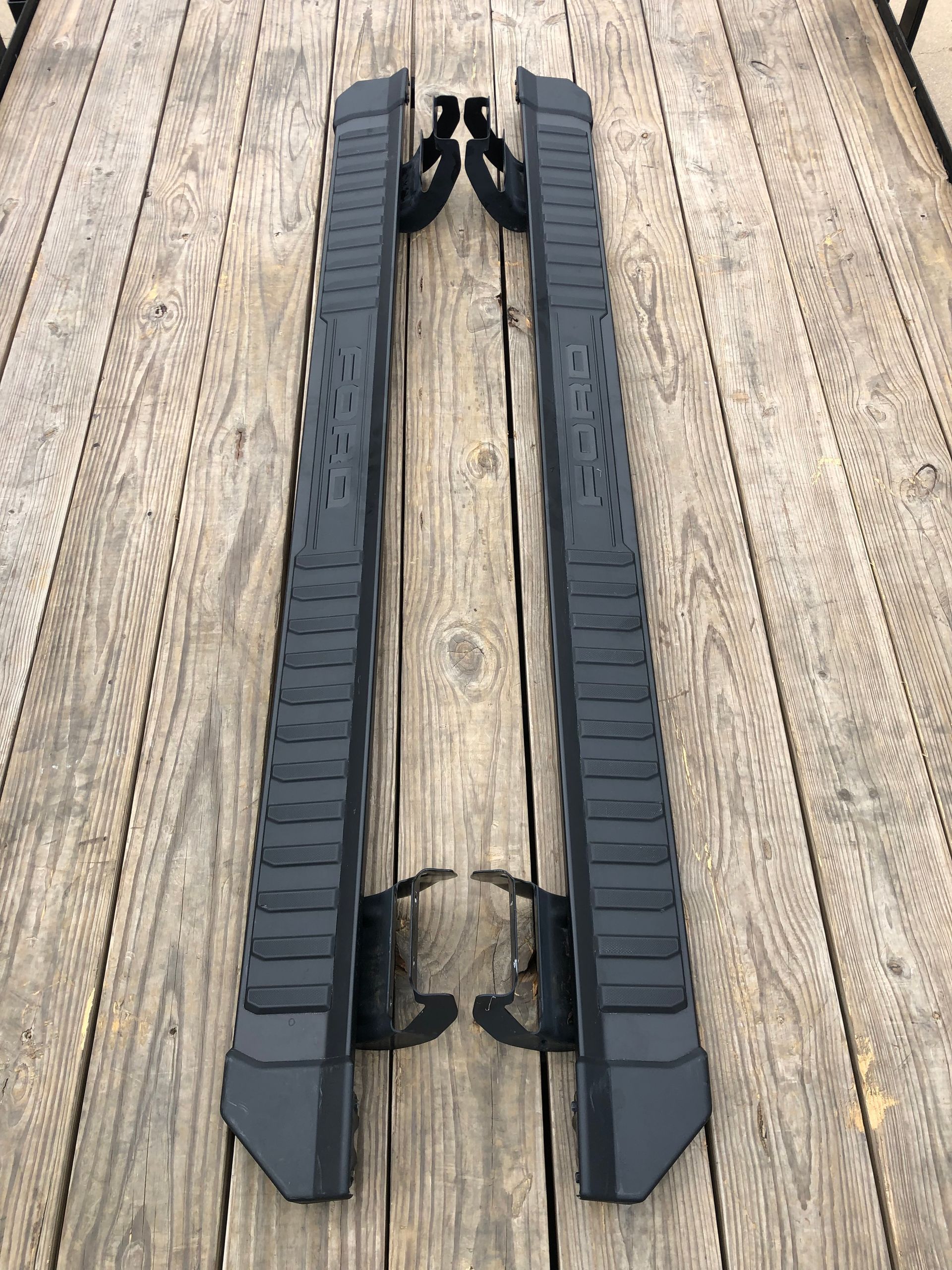 A pair of black side steps are sitting on top of a wooden deck.