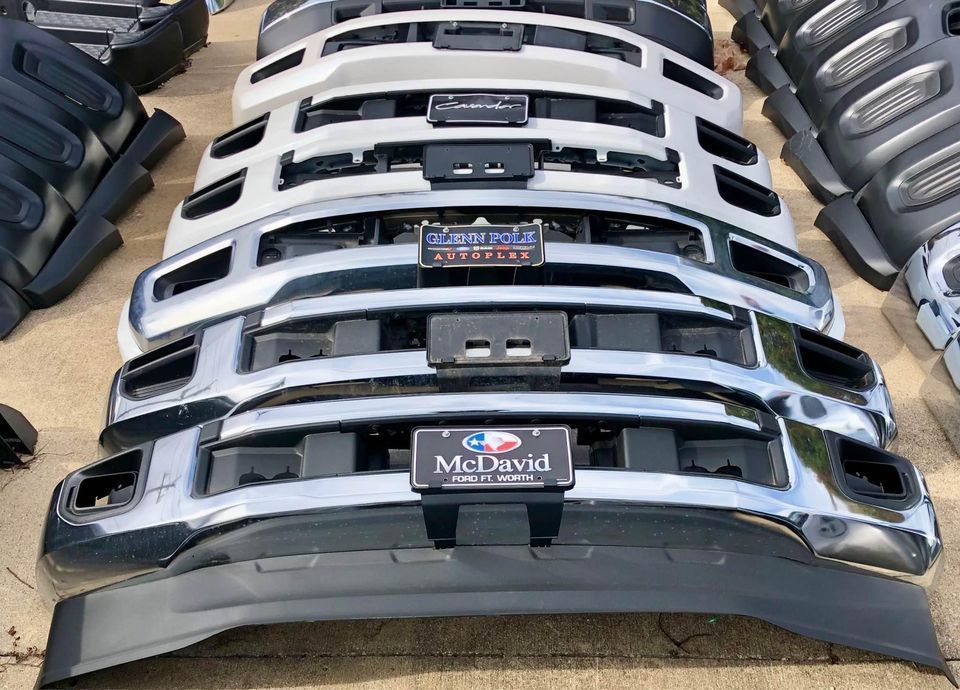 A bunch of front bumpers are stacked on top of each other