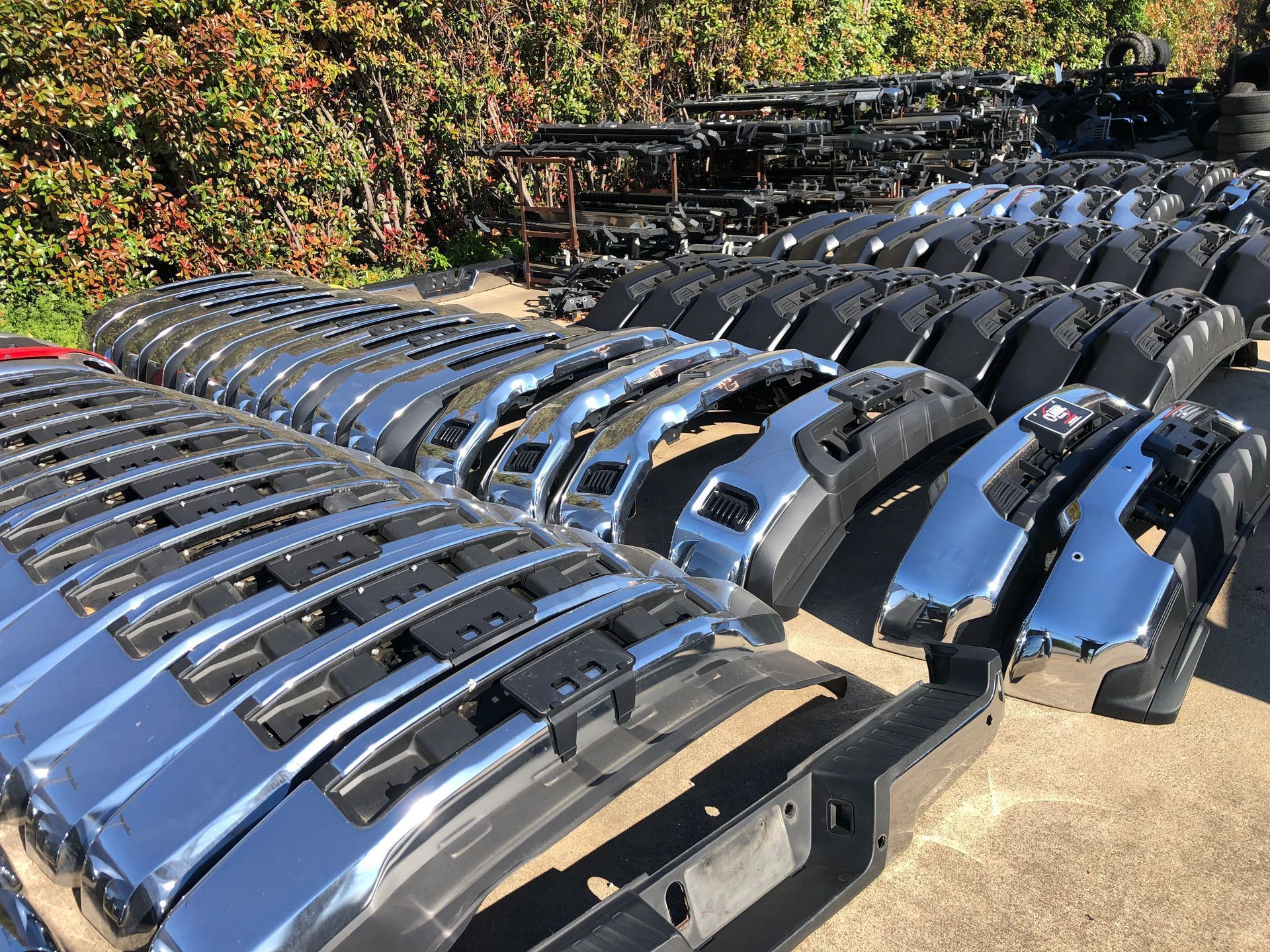 A bunch of chrome bumpers are stacked on top of each other