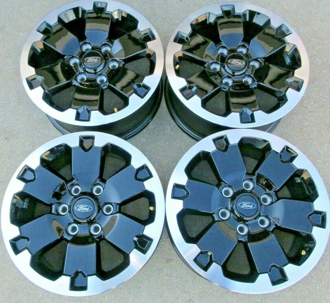 Four ford wheels are sitting on a concrete surface