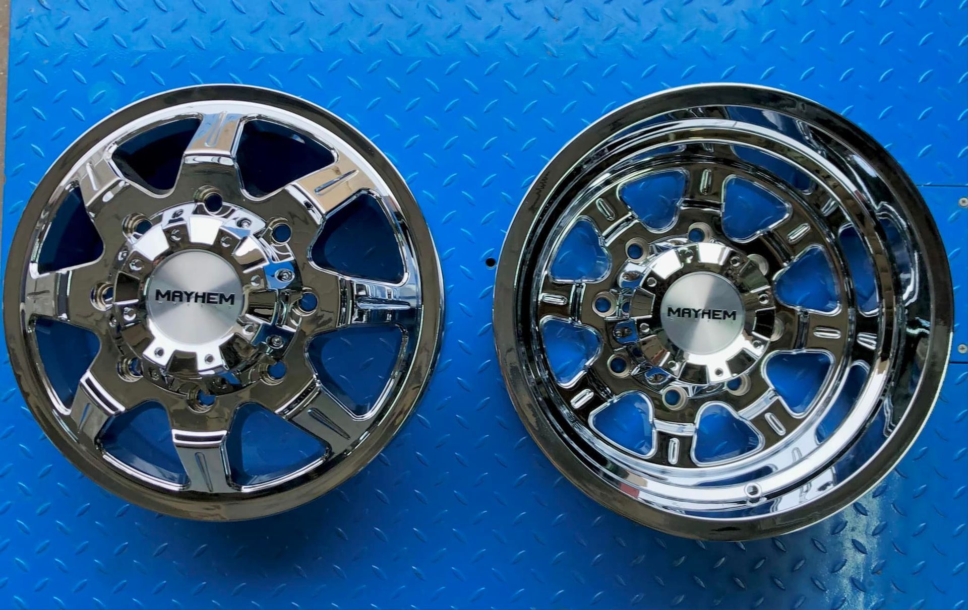 A pair of chrome rims on a blue surface