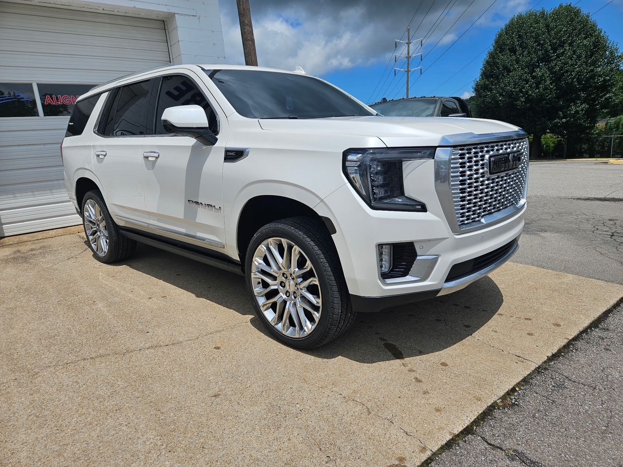 A white gmc yukon is parked in front of a garage door.