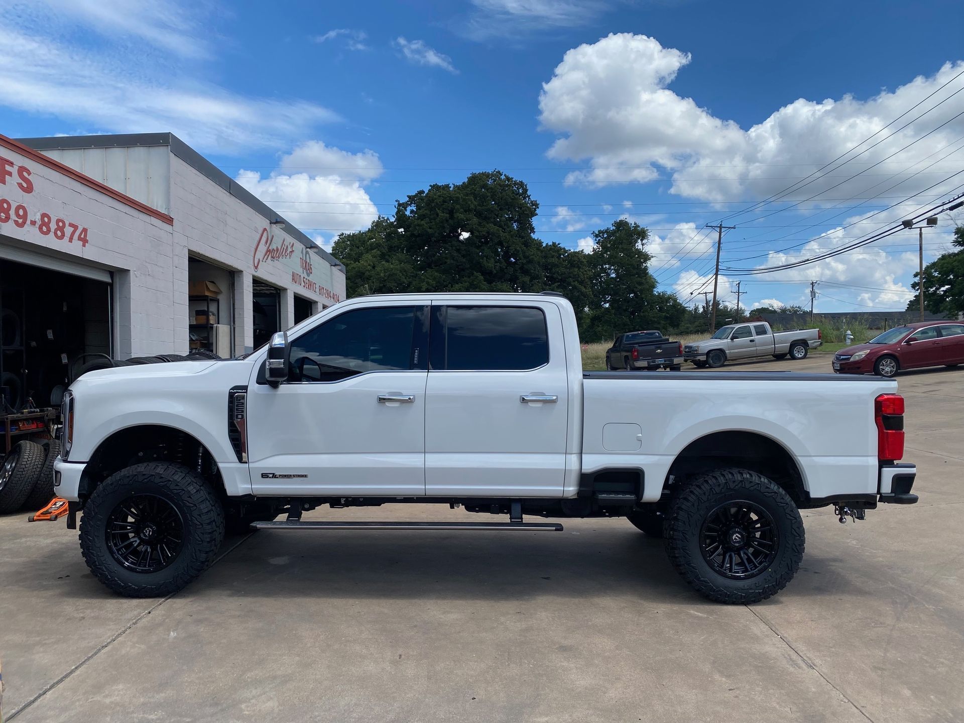 A white pickup truck is parked in front of a garage.