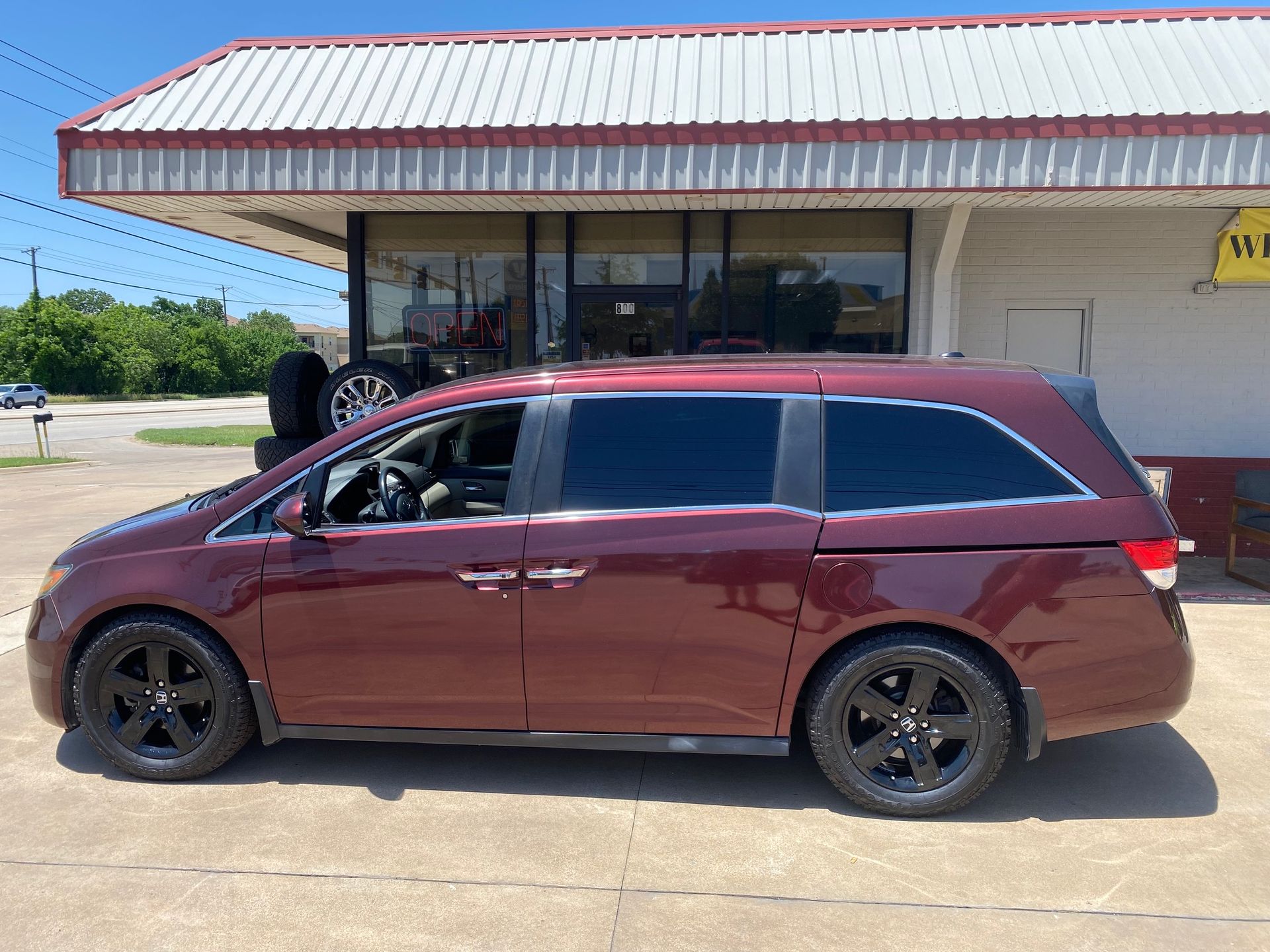 A red minivan is parked in front of a building.