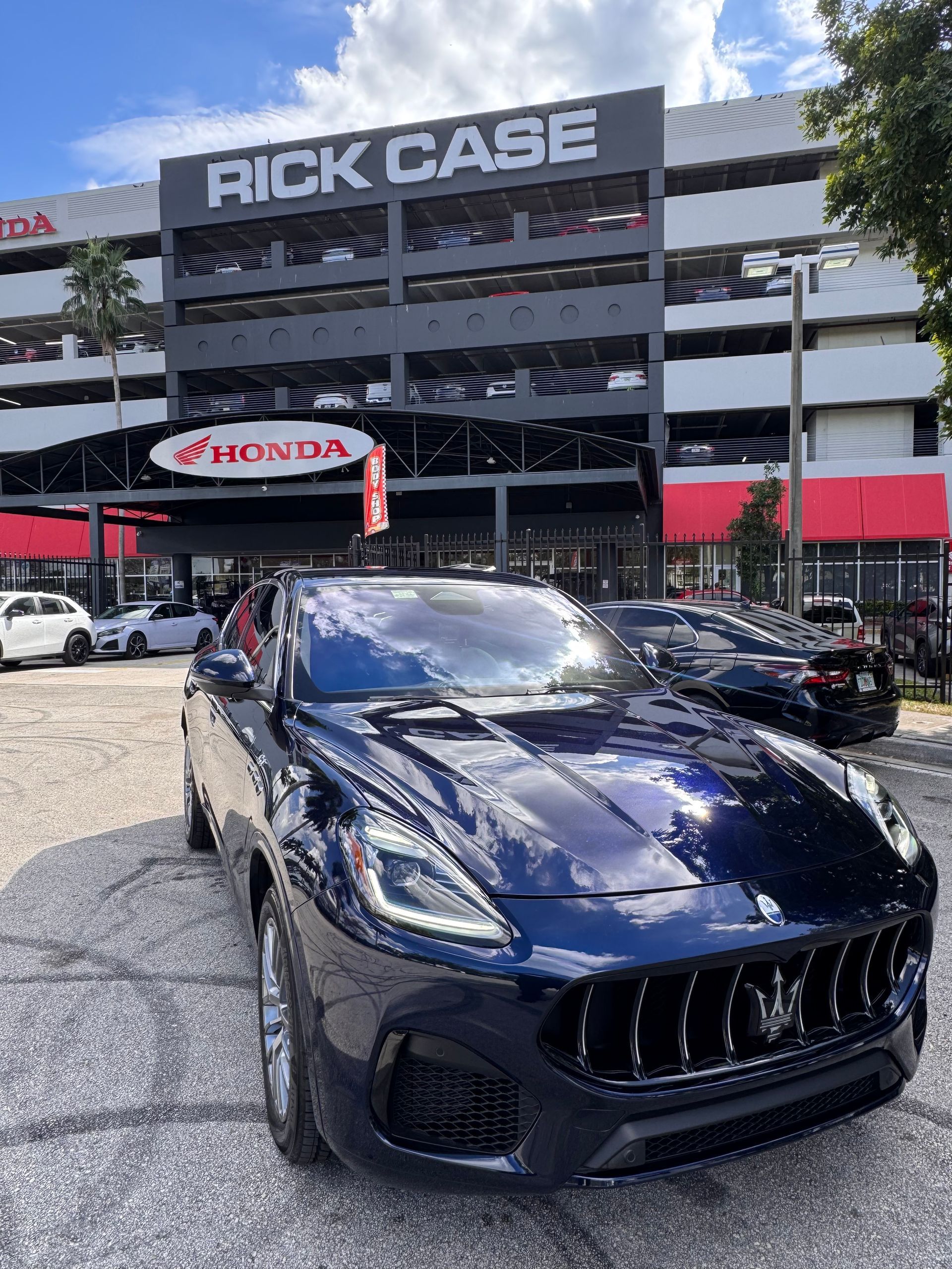 Two men cleaning the windshield of a white car in a parking garage. They are holding red cloths and appear to be working.
