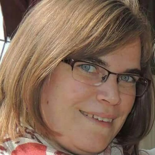 A woman wearing glasses and a scarf is smiling for the camera.
