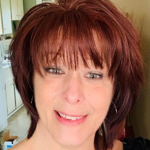 A woman with red hair is smiling for the camera