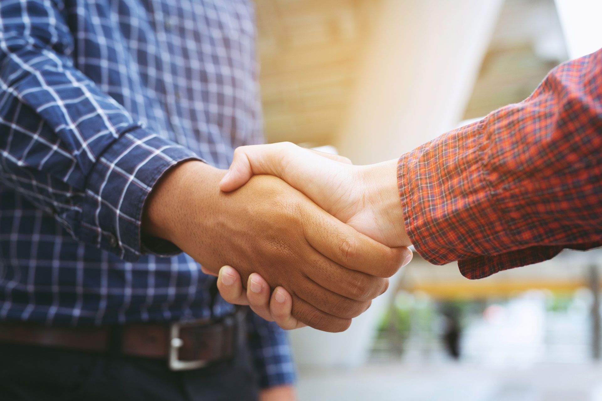 Two men are shaking hands in a close up of their hands.