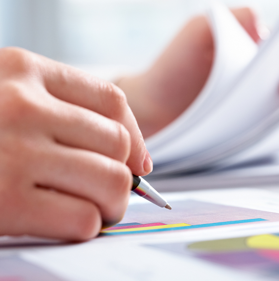 A person is writing on a piece of paper with a pen