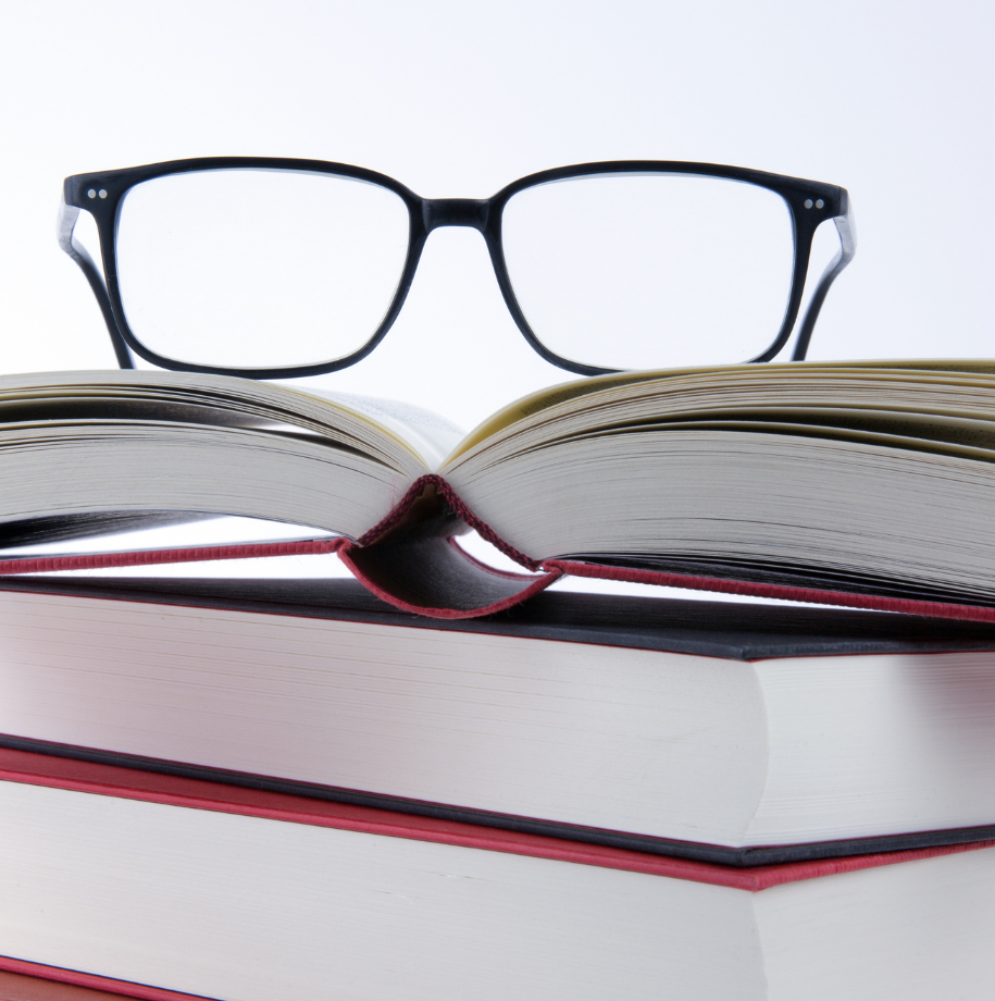 A pair of glasses sits on top of a stack of books