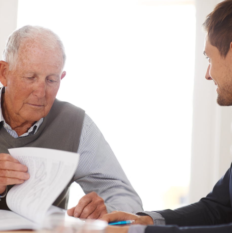 Two men are sitting at a table looking at a piece of paper.