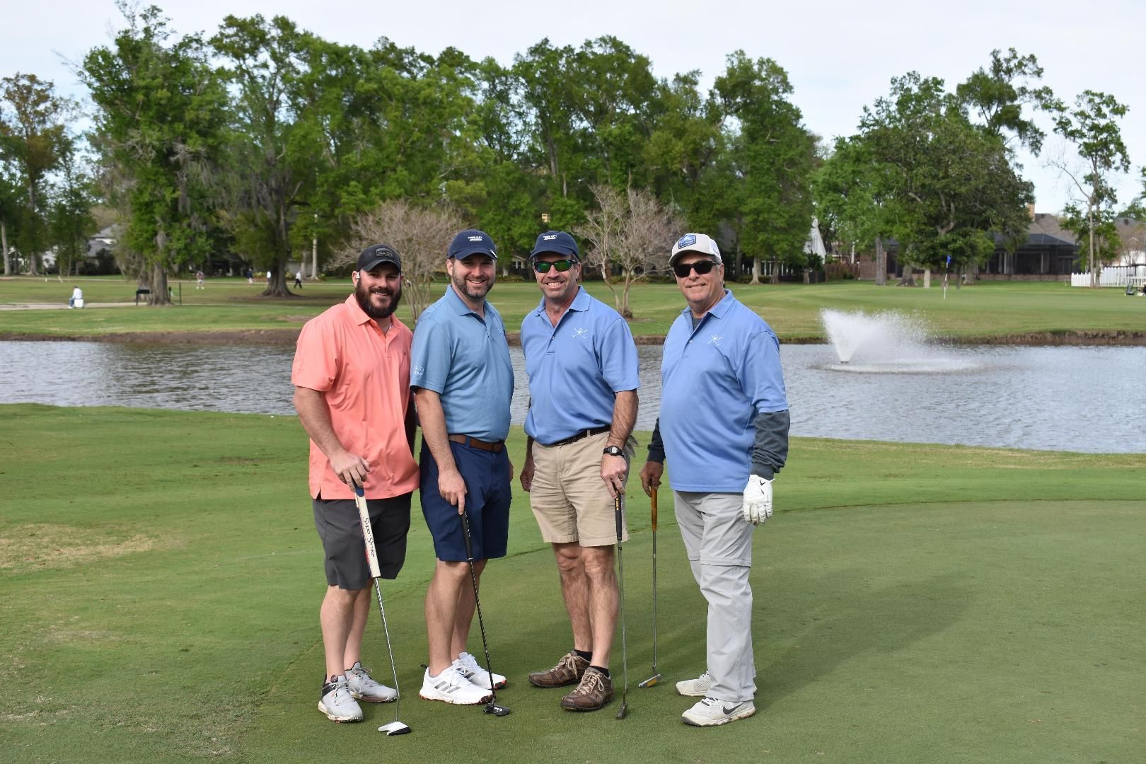 A group of men are standing on a golf course holding golf clubs.