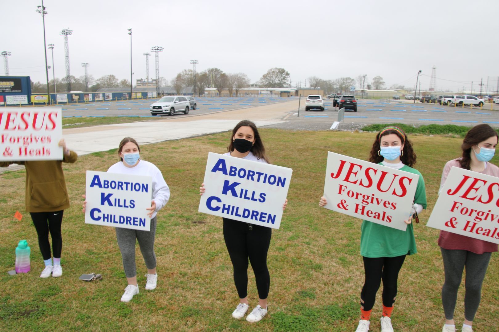 A group of women are holding signs that say abortion kills children and jesus forgives and heals.