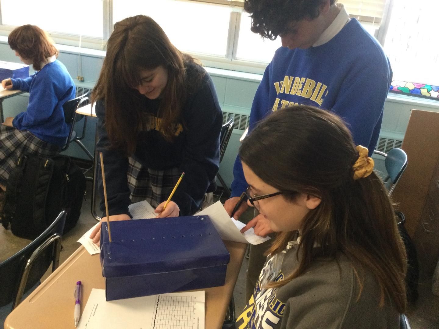 A group of students in a classroom with one wearing a sweatshirt that says ' ucsd ' on it