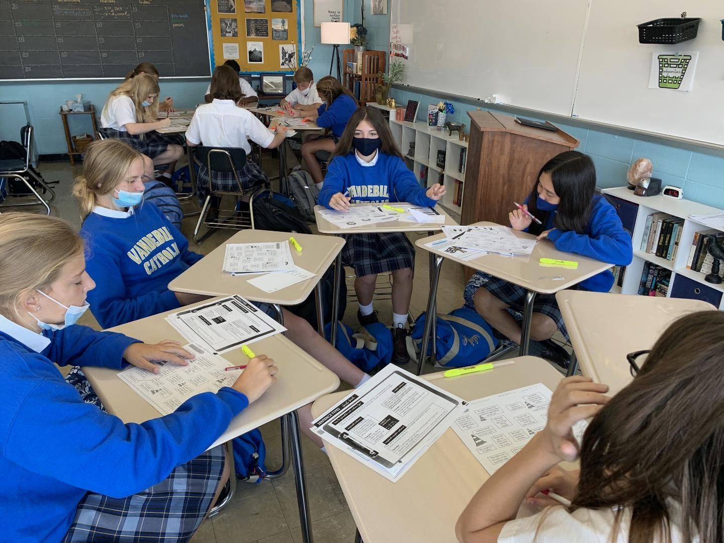 A group of children wearing masks are sitting at desks in a classroom.