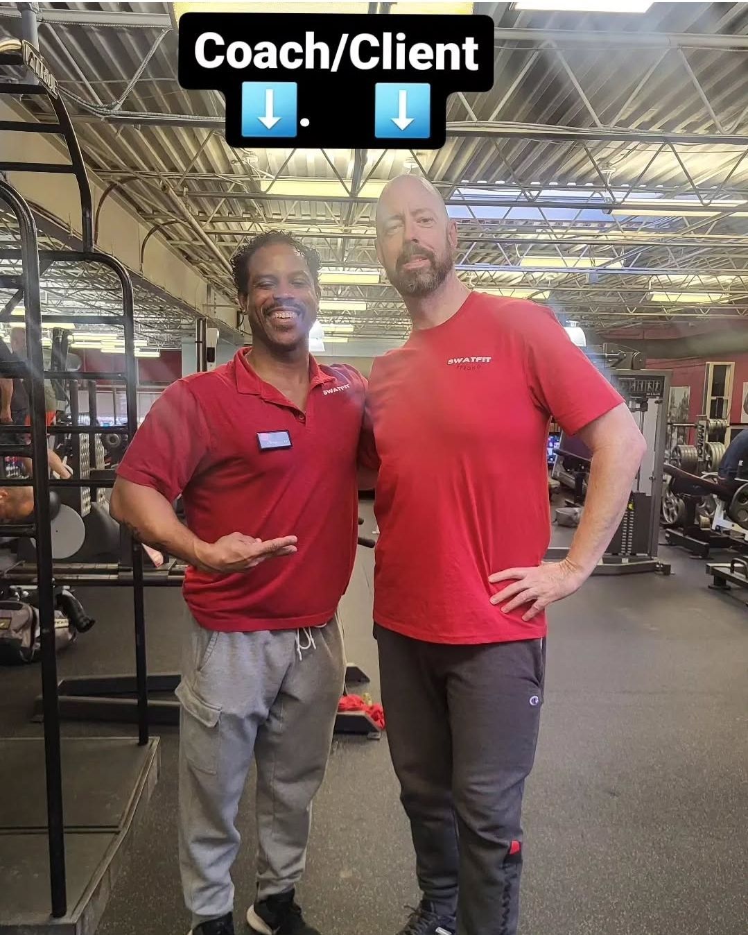 Two men in a gym pose for a photo. One points, both smile. The setting appears to be a fitness center.