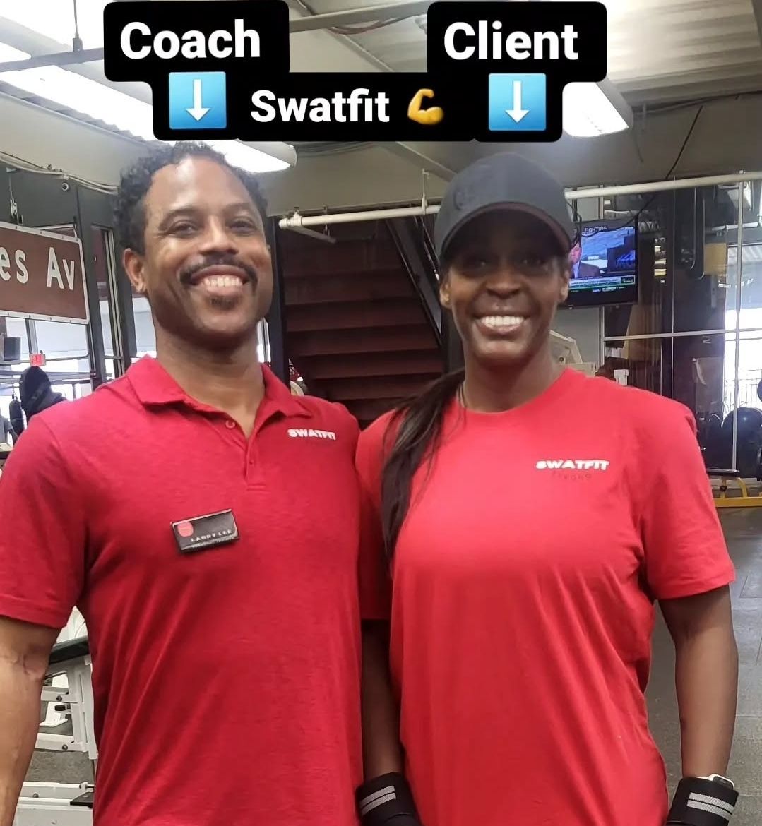 Coach and client smiling together in a gym. Both wear red shirts, 