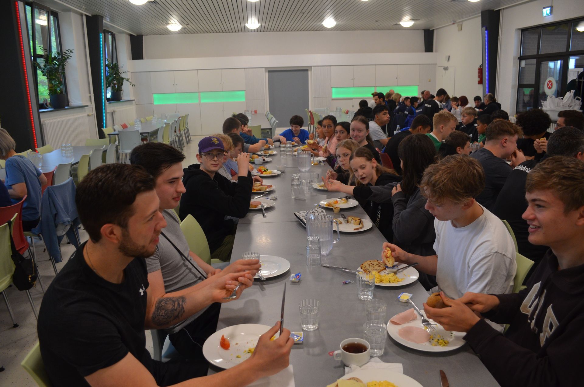 Eine Gruppe Leute sitzt an einem langen Tisch und isst - Karate-Jugendfreizeit.