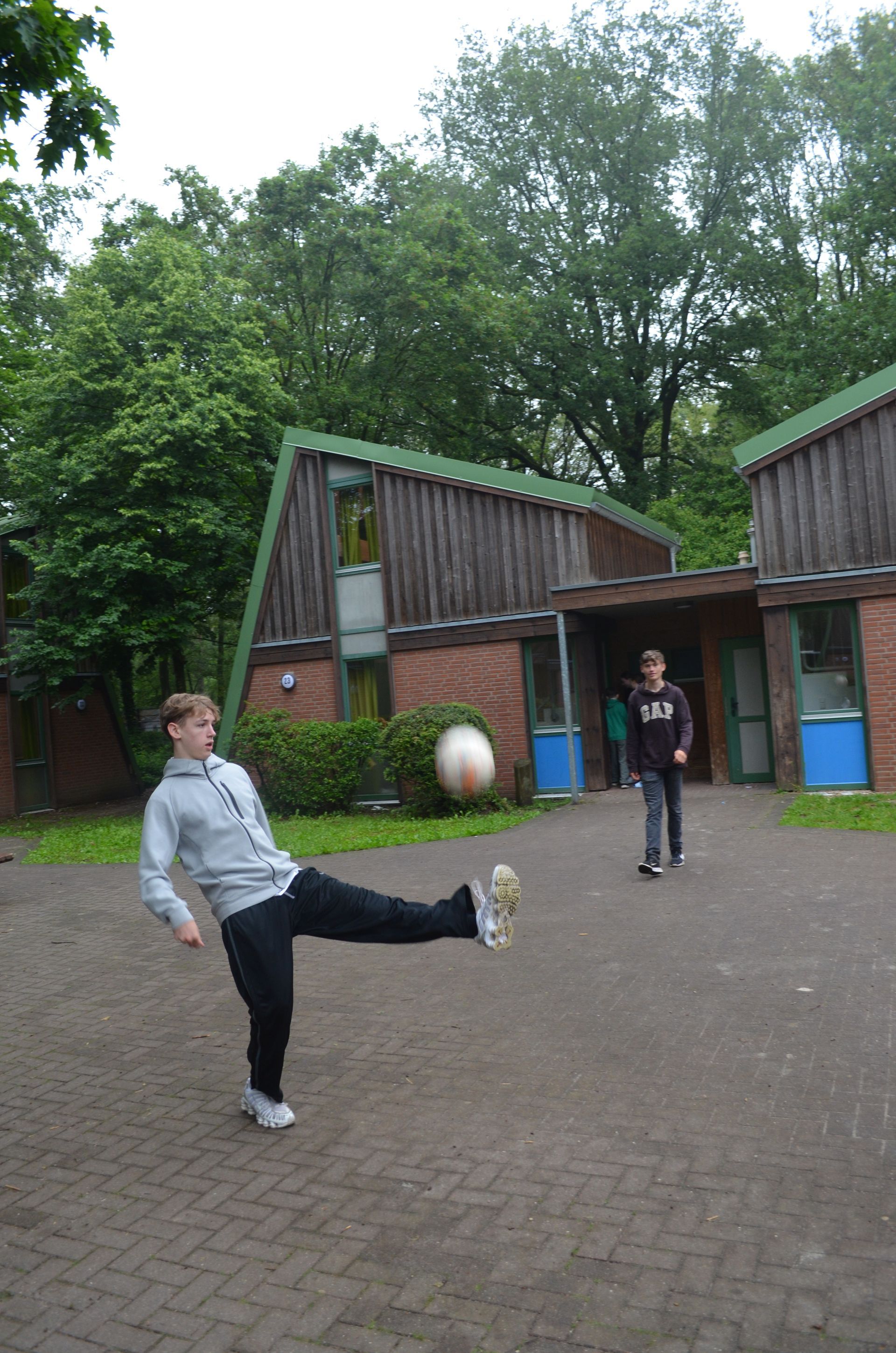 Ein Mann kickt einen Fußball vor einem Gebäude - Karate-Jugendfreizeit.
