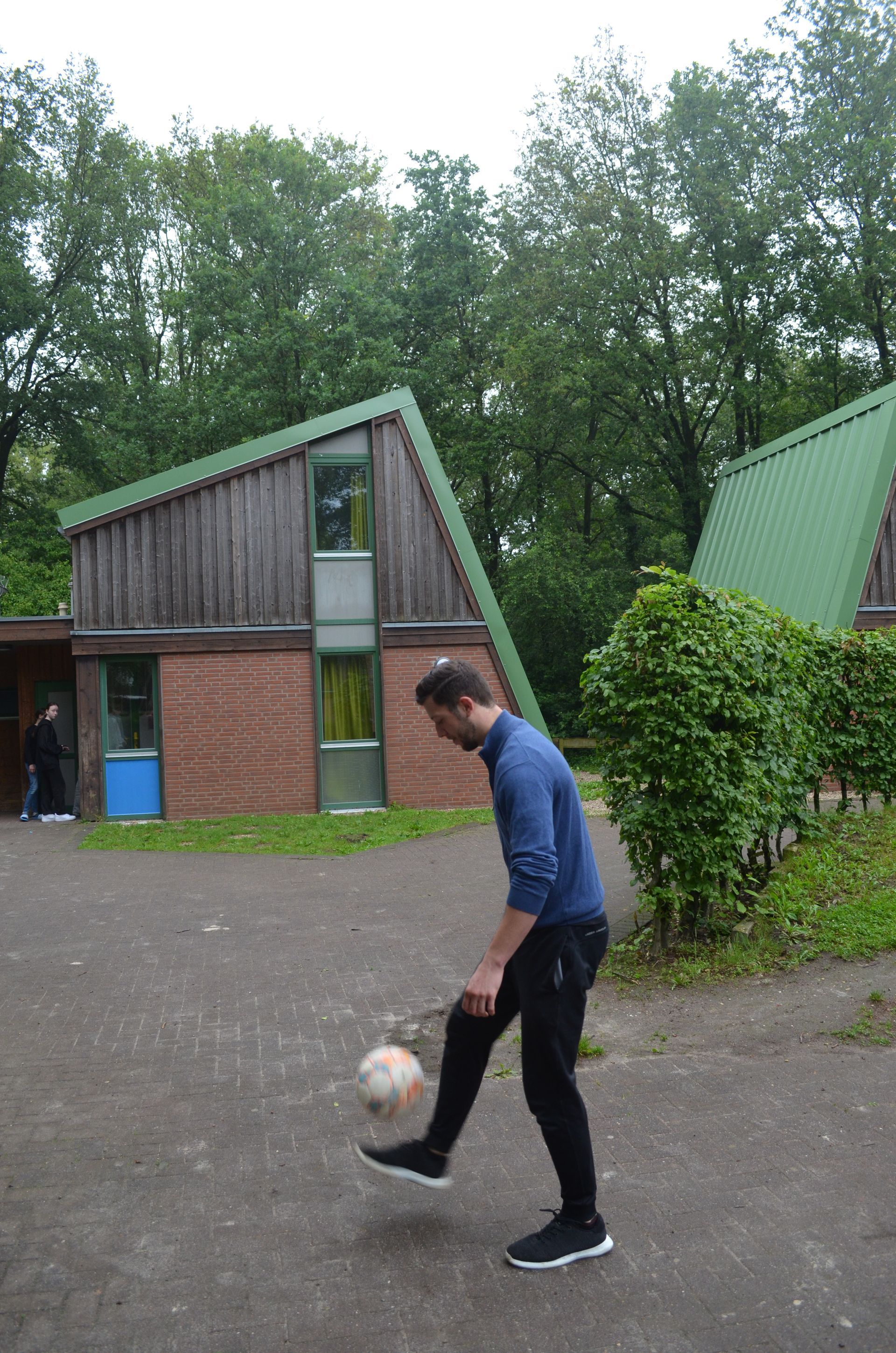 Ein Mann kickt vor einem Gebäude einen Fußball  - Karate-Freizeit.